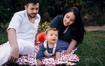 A joyful family enjoying a picnic outdoors during summer. Smiling parents with their baby on a blanket.