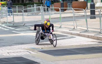 A dedicated athlete competes in a marathon using a racing wheelchair on city streets.